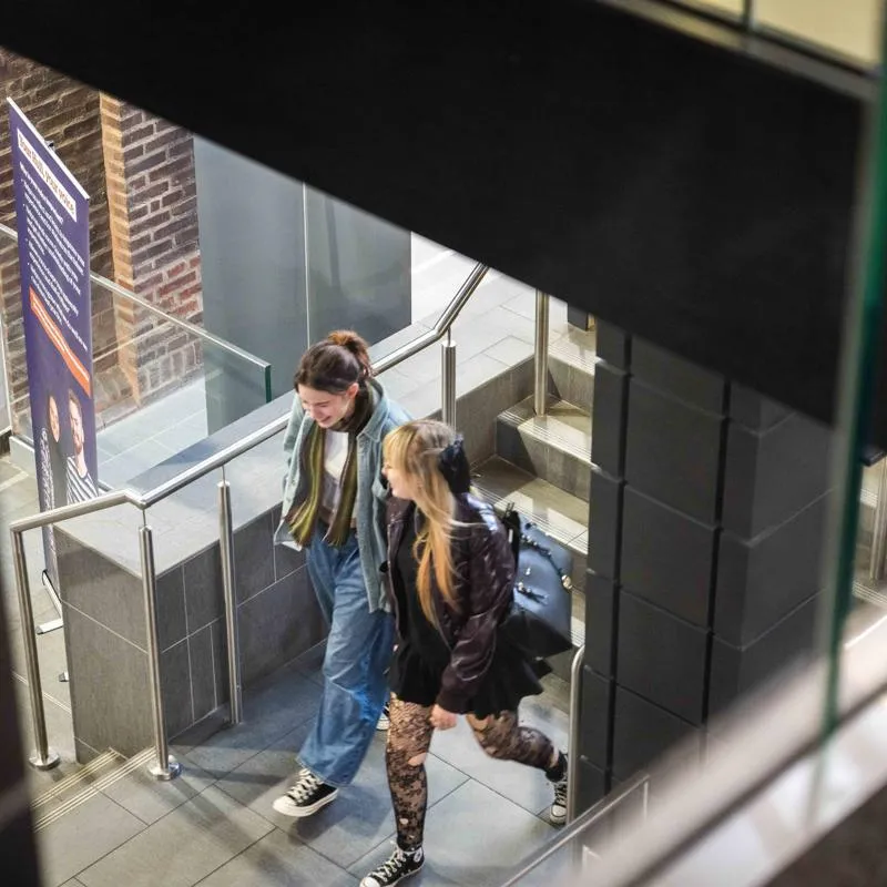 two smiling people on the library stairs