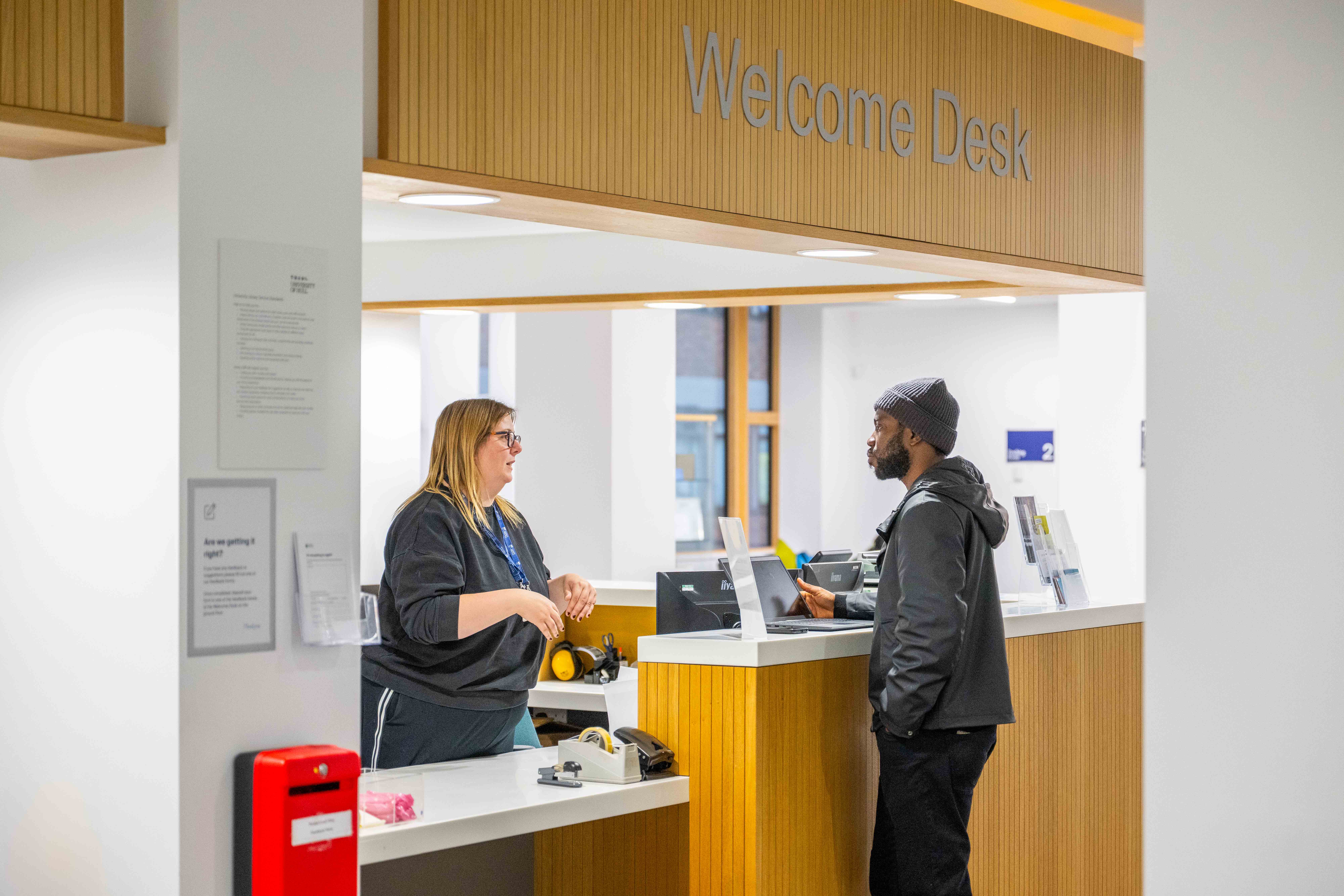 Visitor at the reception desk speaking to a member of the Library Staff